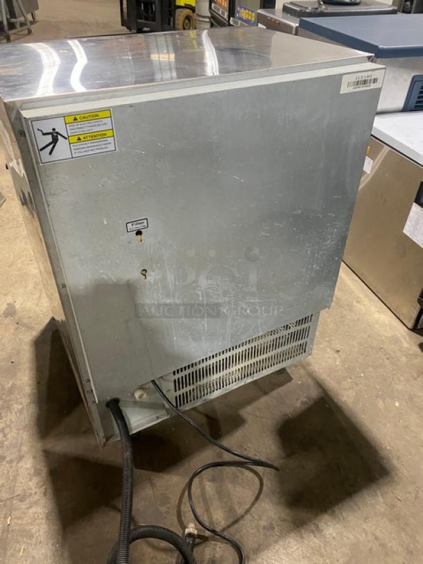 Coldline ICE180 stainless steel undercounter ice maker, electric-powered, air-cooled, on legs, 115V. Visible caution labels.