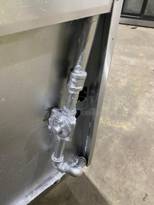 Stainless steel piping component of Jade Range oven, showing silvered gas connections and fittings.