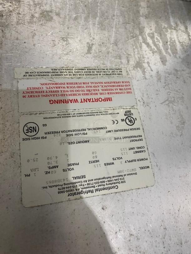 Continental Commercial Stainless Steel 3 Door Refrigerated Prep Table, Model SW72-30M, serial number 143B8865, on casters, features tags with warning and model details.