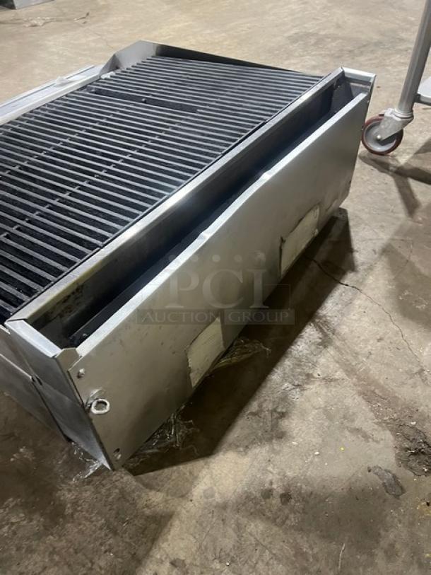 Commercial stainless steel gas-powered countertop char broiler, metal grates, sturdy construction, slight wear visible.