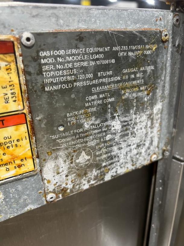 Vulcan LG400 commercial stainless steel deep fat fryer, 50 lb. capacity, natural gas, with backsplash, basket hanger, and fry basket. Model and serial number plate shows Model: LG400, SN: DV-1070061HB. On casters.