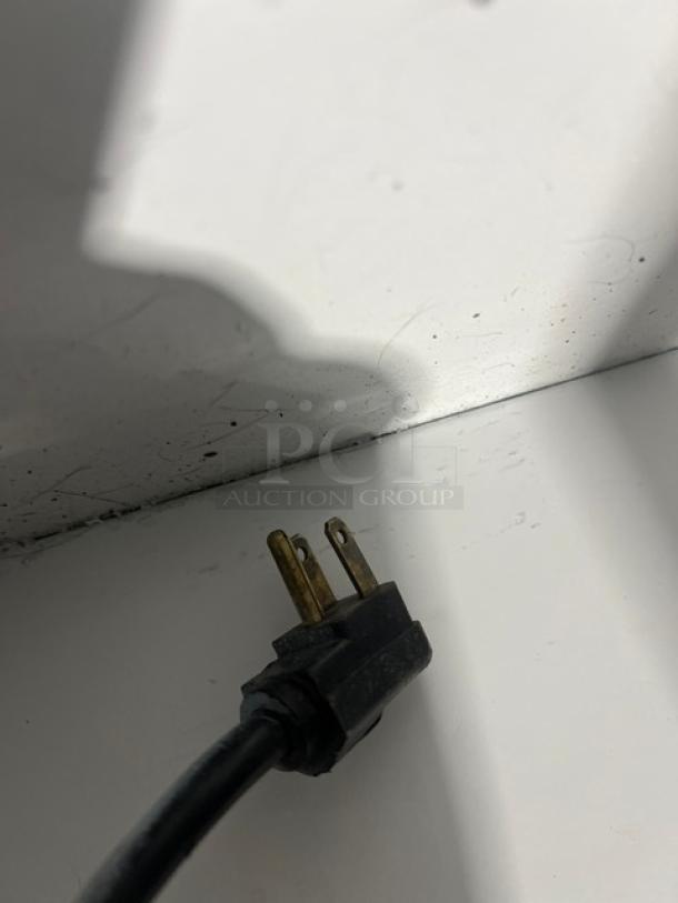 Close-up of electrical plug from Hussmann LBN8 ice cream display freezer, showing 115V 1 Phase connection, slight wear visible.