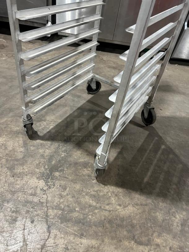 Commercial aluminum full-height bun/sheet pan rack on casters, holds multiple pans, durable, with visible wear.