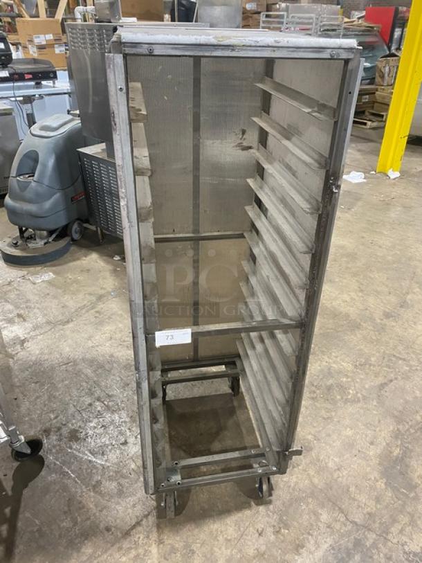 Commercial full-height aluminum bun/sheet pan rack with corrugated sidewalls on casters, visible wear, labeled "73".