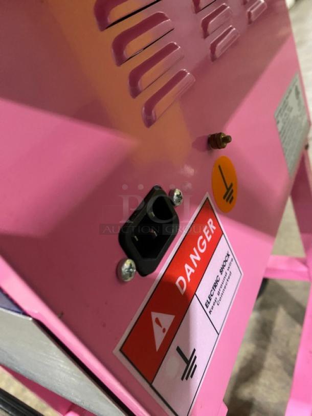 Olde Midway Spin-2000 hot-pink cotton candy machine. Close-up shows warning labels and power socket. Model: CONCOTSP2000CRT.