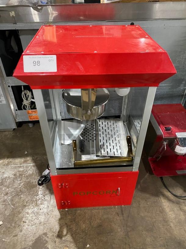 Carnival King red stainless steel popcorn machine with removable kettle, scoop, and storage. Includes stand legs. Auction tag visible.