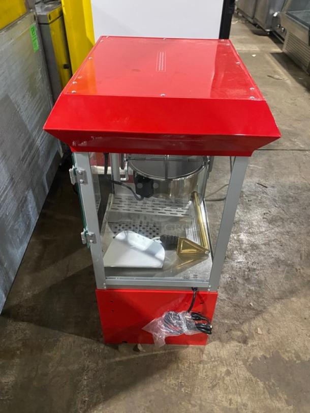 Carnival King red stainless steel electric popcorn machine with removable kettle, popcorn scoop, and storage cabinet.