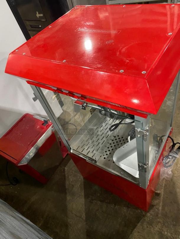 Carnival King red stainless steel electric popcorn machine, with removable kettle, scoop, inner cabinet storage, and stand legs.