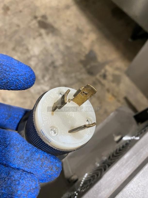 2017 Turbo Chef NGO Rapid Cook Oven plug, 208/240V, 1 phase, visible prongs, gloved hand holding it, good condition.