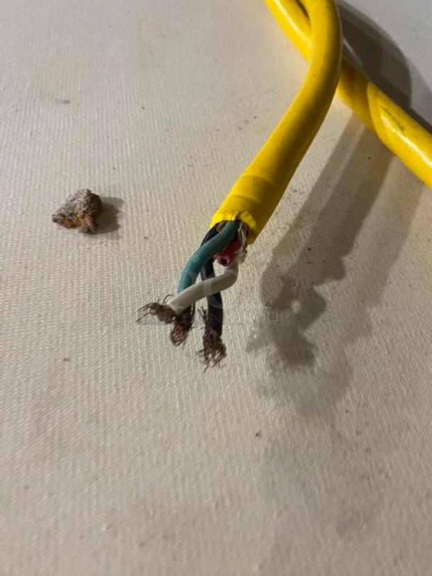 Damaged Rondo floor style belt conveyor system wire with exposed internal cables and yellow external casing, indicating repair needed.