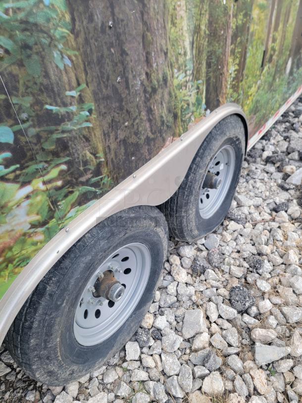 Diamond Cargo 24' Mobile Kitchen Trailer, forest wrap, dual wheels, 14,000 lbs GVWR, 2021 model, on rocky terrain.