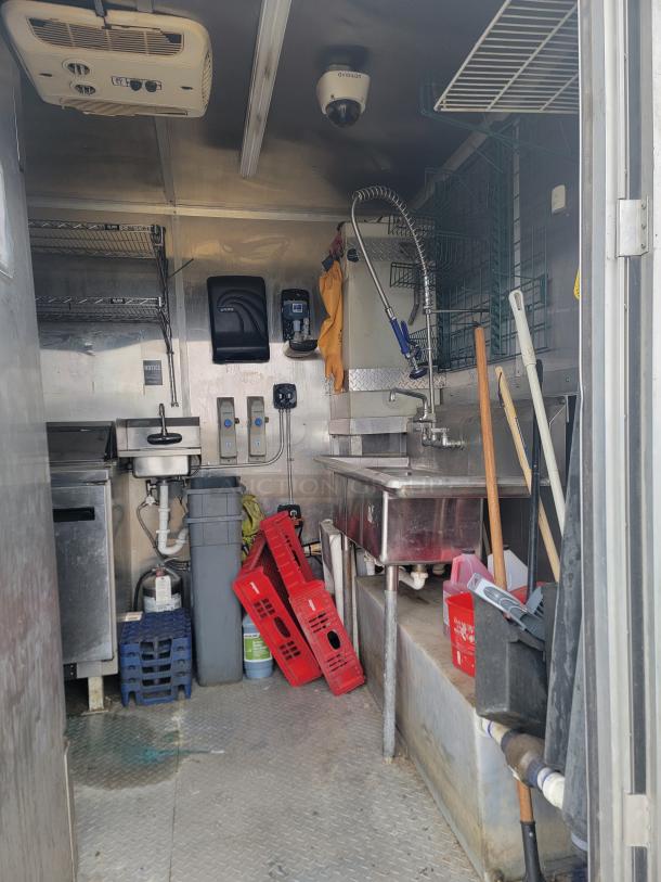 Interior of 2021 Diamond Cargo 24' mobile kitchen trailer, featuring commercial sink, storage shelves, and appliances. 14,000 lbs GVWR.