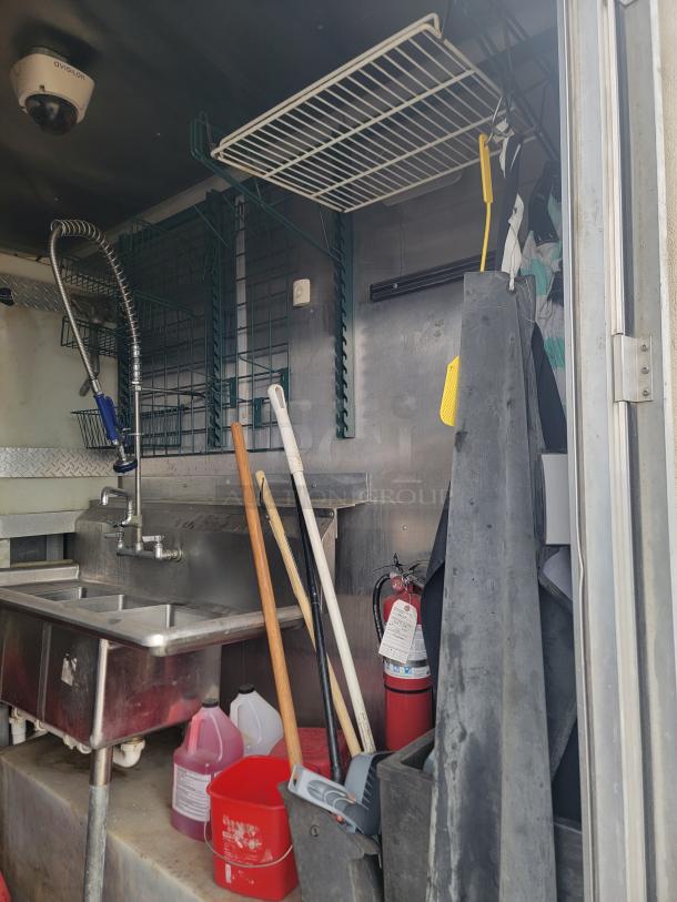 Diamond Cargo 24' mobile kitchen trailer interior with stainless steel sink, cleaning supplies, mop, and fire extinguisher.