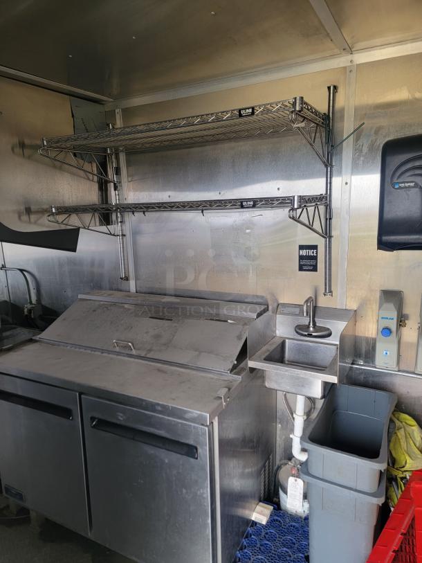 24' Diamond Cargo mobile kitchen trailer, 2021 model. Features stainless steel prep area, sink, shelving, professional wrap.