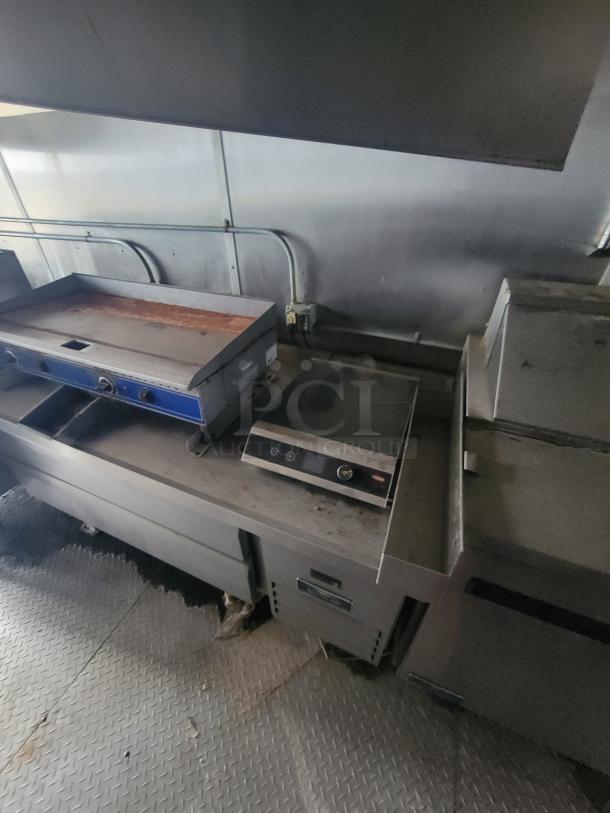 24' Diamond Cargo mobile kitchen trailer interior with stainless steel equipment, featuring a griddle and control panel.