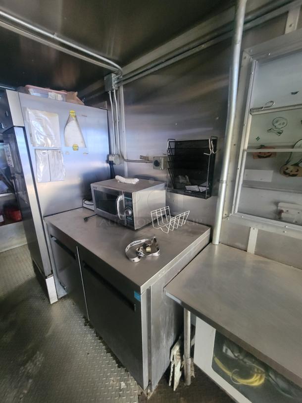 Fully equipped 24' mobile kitchen trailer interior featuring stainless steel counters and appliances, ready for culinary use.