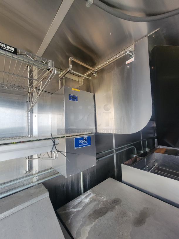 Interior of a 24' Diamond Cargo mobile kitchen trailer, featuring a stainless steel commercial-grade setup with shelving and a Pyro-Chem Model K fire suppression system.