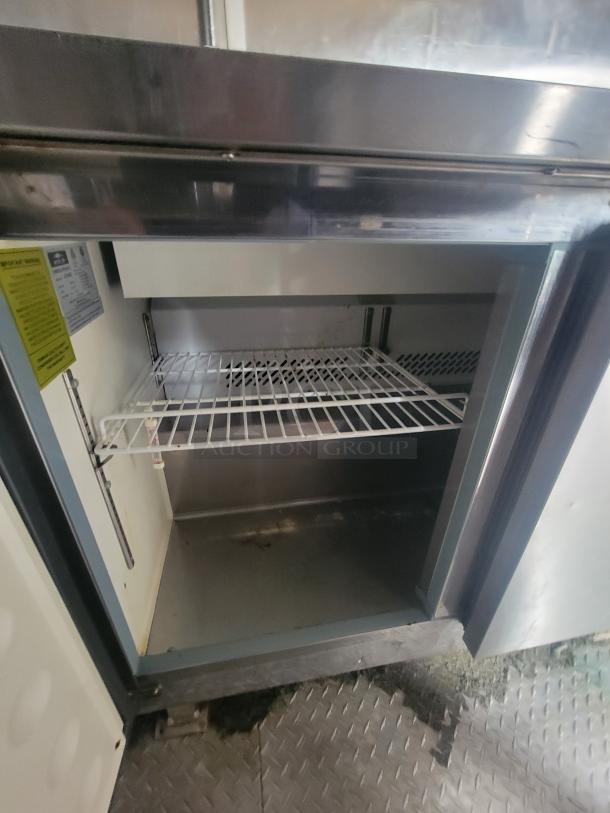 Inside view of a commercial fridge with a wire shelf, part of a Diamond Cargo 24' Mobile Kitchen Trailer, 2021 model.