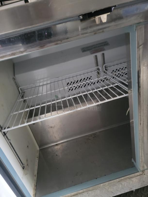 Interior view of a 2021 Diamond Cargo 24' mobile kitchen trailer with a metal shelf, showing durable stainless surfaces.
