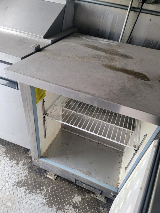 Diamond Cargo mobile kitchen trailer interior, showing stainless steel counter and storage unit, some wear visible.
