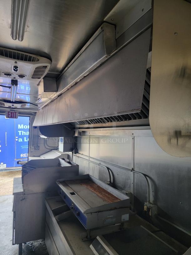 Interior of a 2021 Diamond Cargo 24' mobile kitchen trailer, featuring a professional-grade kitchen setup with ventilation hood and griddle.