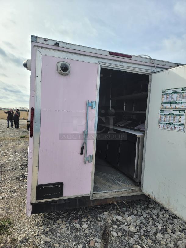 Haulmark 24' mobile kitchen trailer, pink exterior, open side door showing interior with commercial equipment.