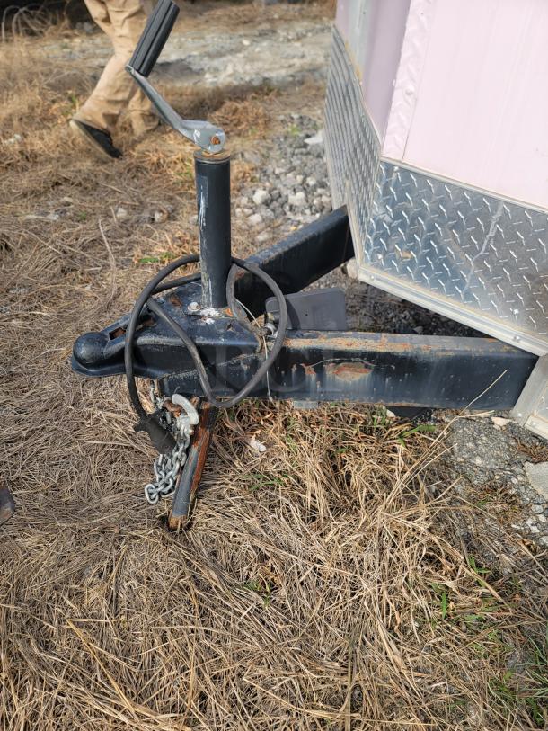 Haulmark 24' mobile kitchen trailer hitch, featuring a crank handle, safety chains, and visible wear.