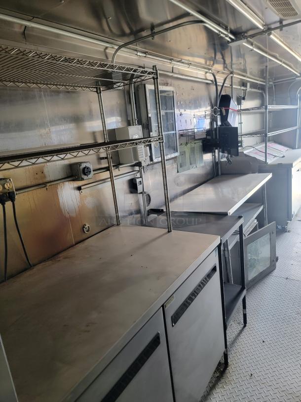 Haulmark 24' mobile kitchen with stainless steel counters, shelving, and commercial refrigerator. Equipped for high-volume service.