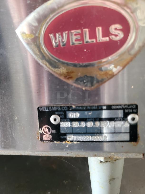Metal label on a Wells appliance displaying model info, UL listing, and electrical specifications. Slight rust visible.