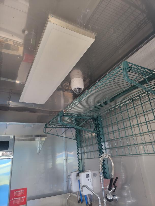 Interior view of Texino FD-306 mobile kitchen, featuring stainless steel surfaces, commercial sink, and wire racks.
