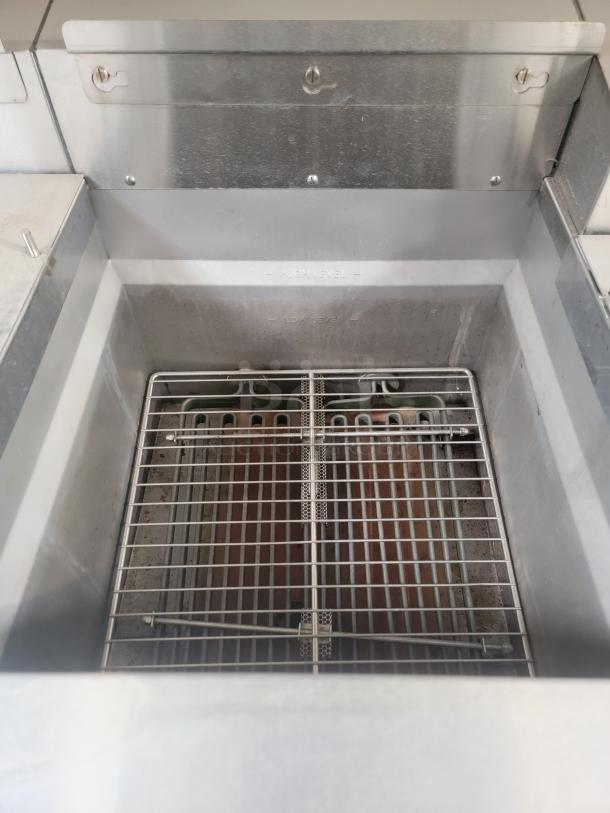 Stainless steel interior of Texino FD-306 mobile kitchen, featuring a robust metal grate and visible usage marks, needing deep cleaning.