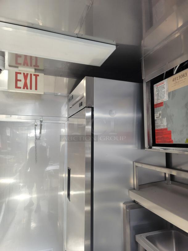 Interior of 2021 Texino FD-306 mobile kitchen, featuring stainless steel surfaces, True refrigeration unit, and several shelves. Needs cleaning.