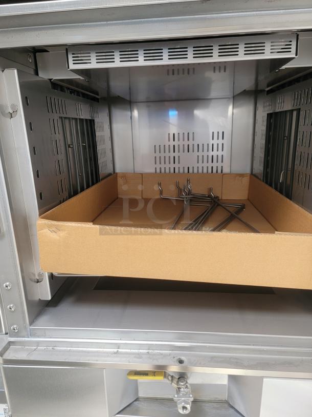 Interior of Texino FD-306 mobile kitchen, showing stainless steel convection oven compartment with cardboard tray and metal hooks.