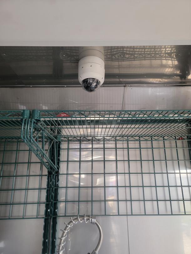 Interior of 28' Texino mobile kitchen showing green wire shelving, stainless steel walls, and a mounted security camera.