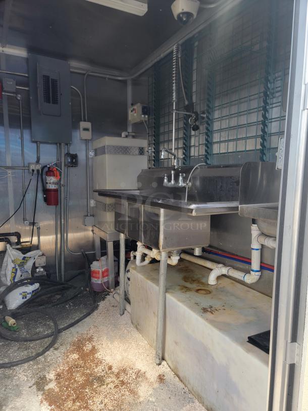 2020 Diamond Cargo mobile kitchen interior featuring a stainless steel sink setup with plumbing, electrical panel, and fire extinguisher.