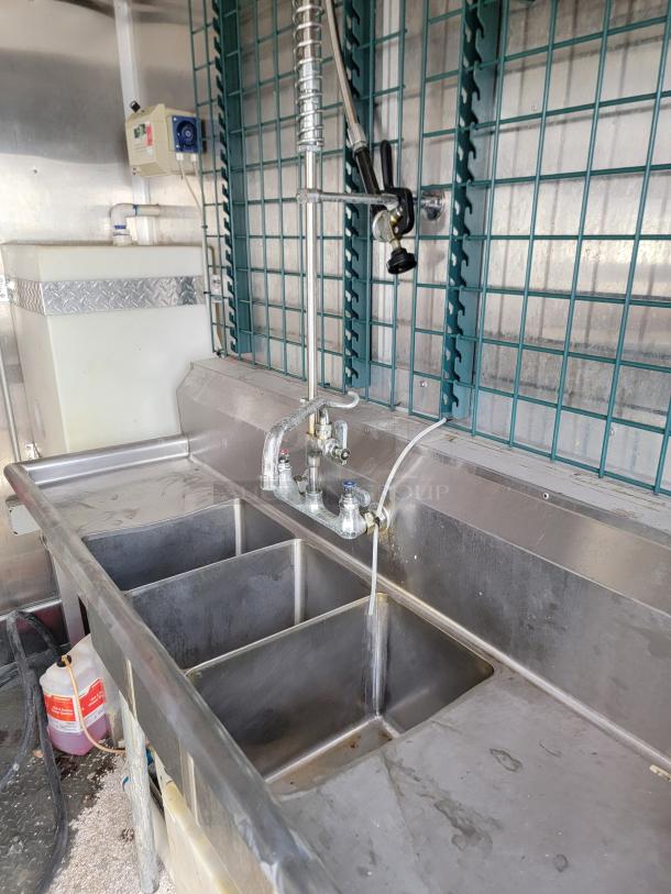 Commercial-grade 3-compartment sink in 2020 Diamond Cargo mobile kitchen, stainless steel with faucet, ready for high-volume use.