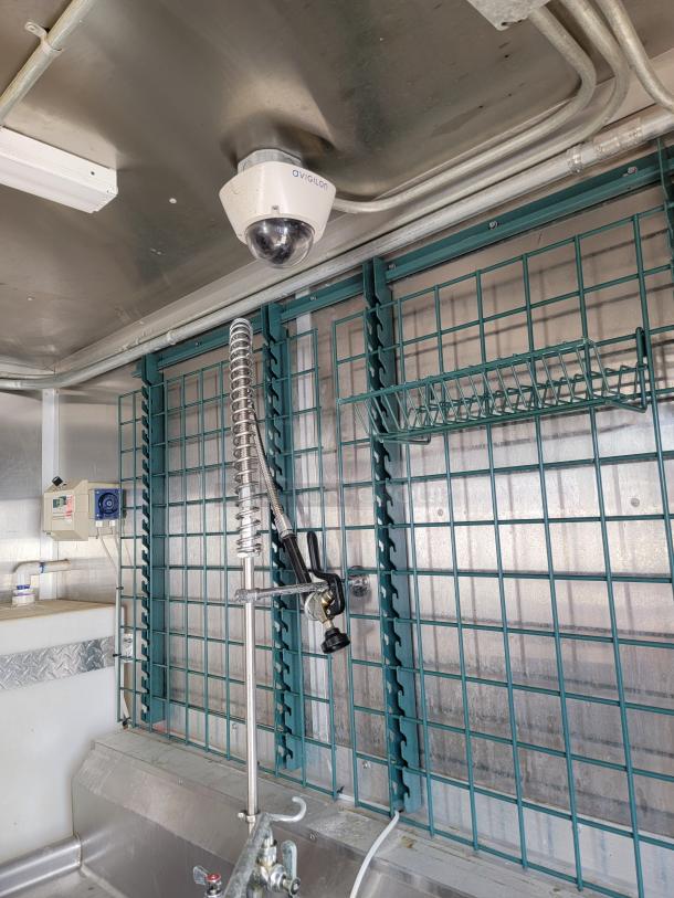 Interior of 2020 Diamond Cargo Mobile Kitchen showing equipment racks, a sink with a sprayer, and an Avigilon camera.