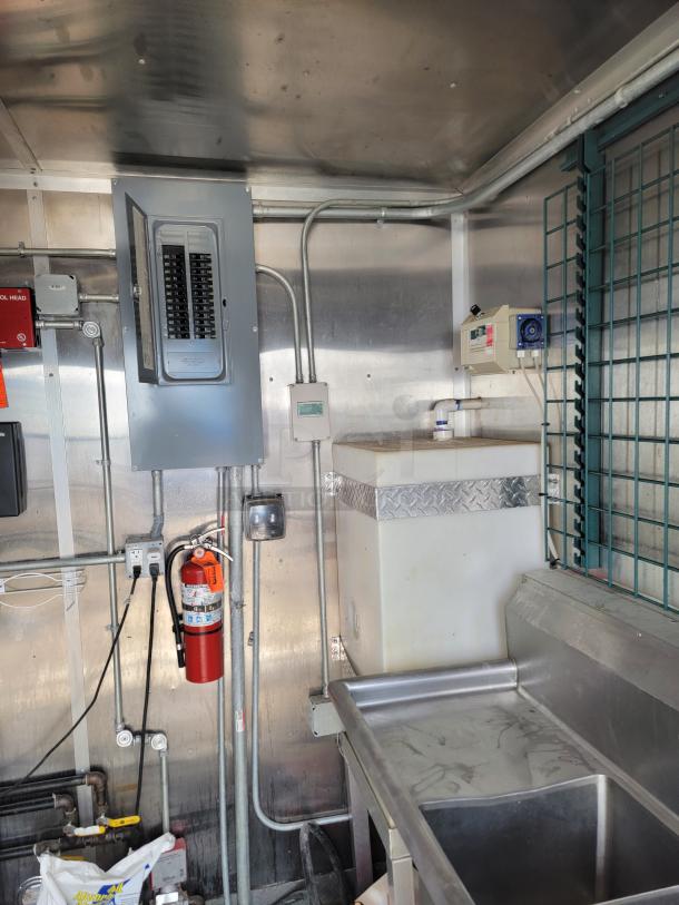 Interior of a 2020 Diamond Cargo 24' mobile kitchen with stainless steel sink, electrical panel, and fire extinguisher.
