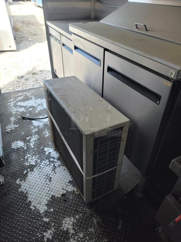 Diamond Cargo mobile kitchen interior showing True prep station and refrigeration unit, with diamond plate flooring.