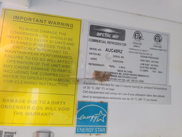 Warning label and Arctic Air refrigerator tag indicating model AUC48RZ, refrigerant type R600a, and energy rating details.