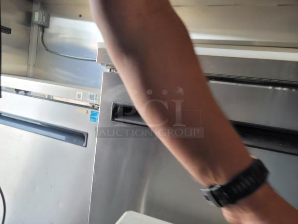 Interior of a Diamond Cargo mobile kitchen showcasing stainless steel appliances, including an Arctic Air refrigerator.