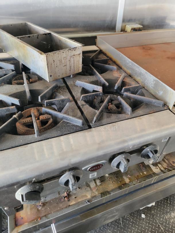 Wells commercial griddle and range with dual burners, showing wear. Part of a 2020 Diamond Cargo mobile kitchen setup.