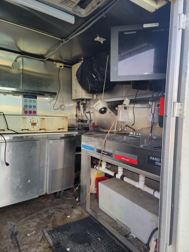 2019 Quality Cargo 24' mobile kitchen interior, featuring Garland range, dirty counters, and Great Lakes TV monitor. Needs cleaning.