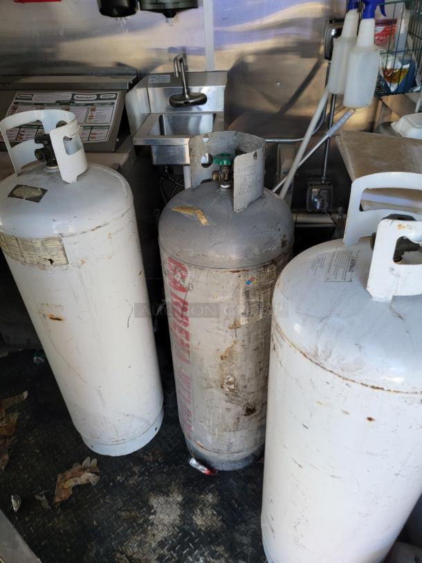 Propane tanks inside a 2021 Diamond Cargo 24' mobile kitchen. Stainless steel sink and storage visible in the background.