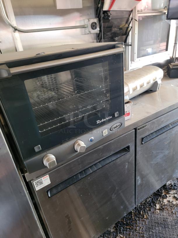 2021 Diamond Cargo 24' mobile kitchen with Cadco oven and refrigerated storage, showing stainless steel interior and cooking equipment.