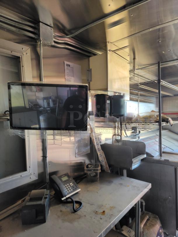 Interior of 2021 Diamond Cargo mobile kitchen with stainless steel surfaces, phone, and mounted security monitor.