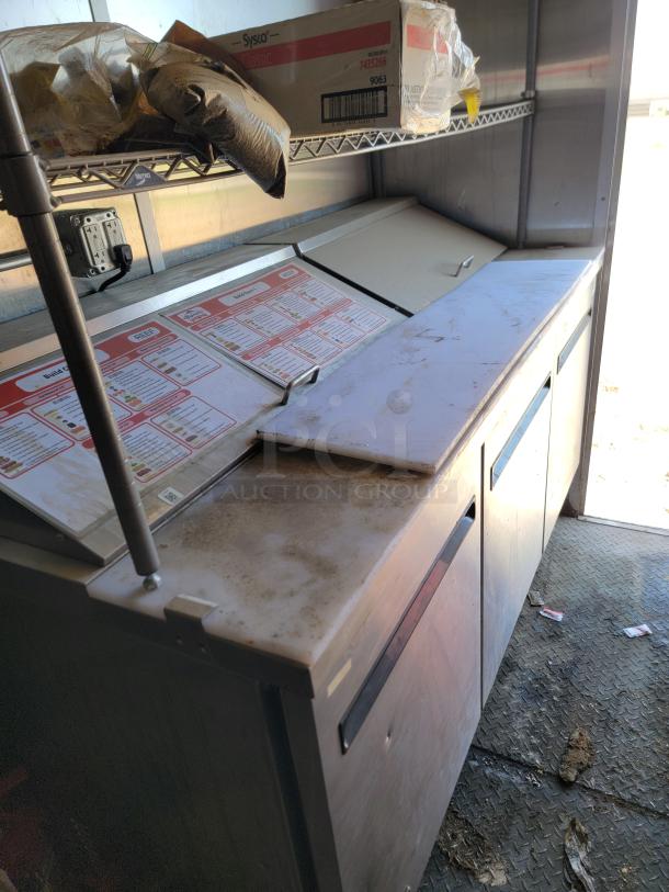 2021 Diamond Cargo 24' mobile kitchen interior, featuring a prep station with menu inserts and storage. Some wear visible.