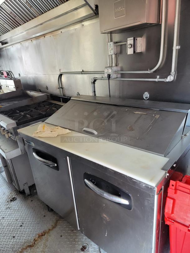 2021 Diamond Cargo mobile kitchen interior with a refrigeration unit, Ansul fire system box, and ventilation hood, in used condition.