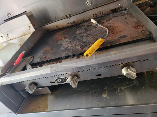 Royal grill inside a 2021 Diamond Cargo 24' mobile kitchen, showing moderate wear with a cleaning brush and utensils.