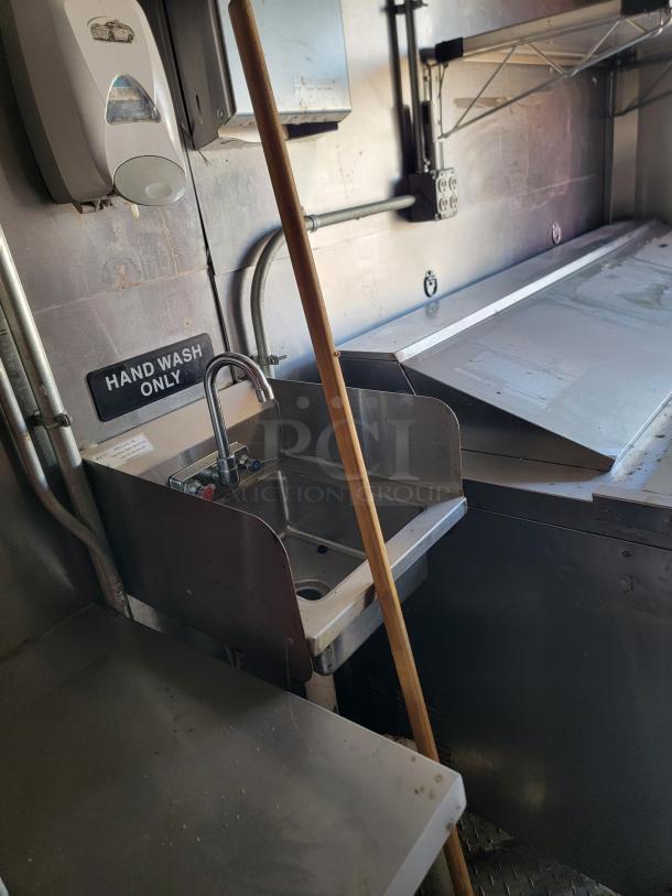 Stainless steel sink area in a 2021 Diamond Cargo mobile kitchen with "Hand Wash Only" sign and soap dispenser.